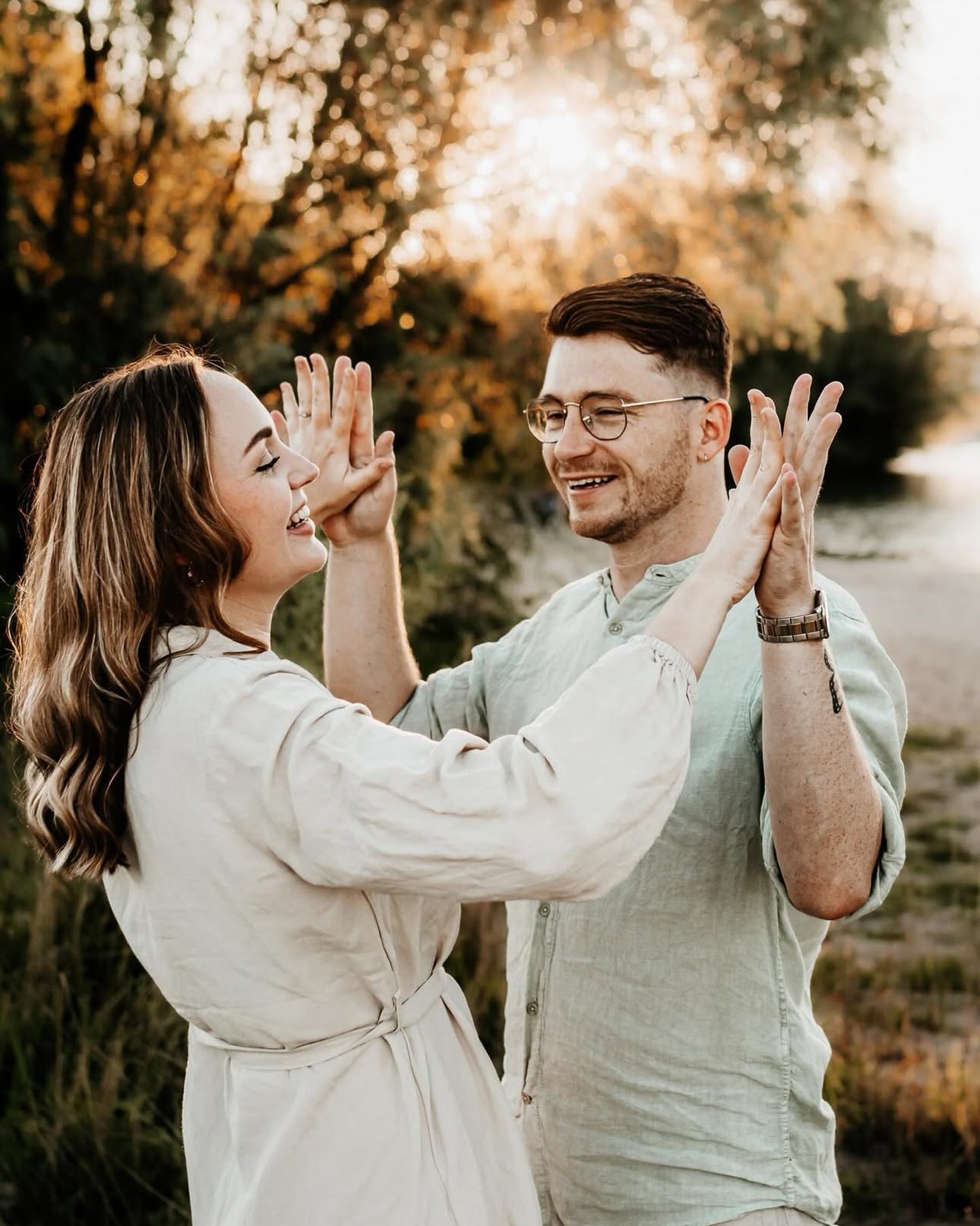 Stel geeft elkaar lachend een dubbele high five in de avondzon
